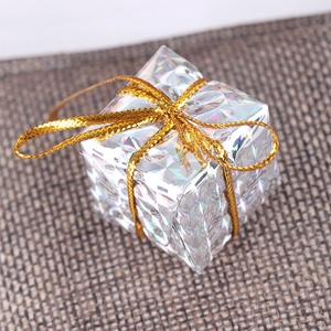 Detail of a 2.5cm silver laser Christmas gift box ornament with a gold ribbon bow