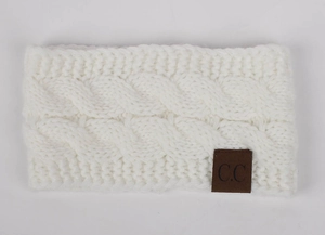 Detail view of white cable knit headband featuring a textured weave and leather C.C tag
