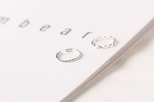 Detail of silver twisted rope and wave stacking rings on an open book page
