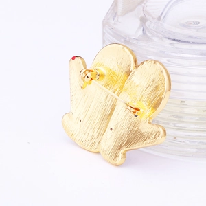 Golden Christmas glove brooch back view with safety pin clasp on textured glass