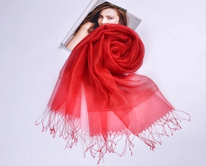 Close-up of red silk organza scarf showing translucent texture and gold tassel details