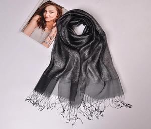 Close-up of black silk organza scarf featuring metallic threads and elegant fringe tassels