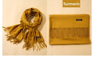 Detail of ginger yellow scarf showing soft fringe and a Cashmere label on fabric