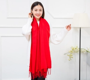 Close-up of soft red cashmere-like scarf with fringe tassels on white knit sweater
