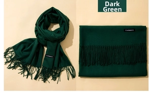 Detail of dark green cashmere scarf showing tassels and fabric texture in a luxury fold