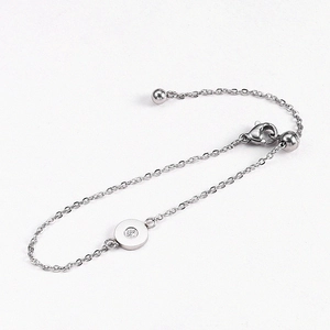 Macro detail of minimalist stainless steel thin chain bracelet with a single crystal round charm