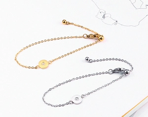 Detail view of gold and silver minimalist O-link bracelets with a single diamond round pendant