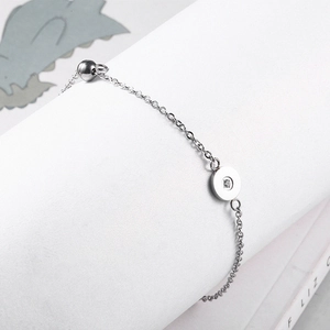 Detail of silver stainless steel bracelet with a round crystal-set pendant charm