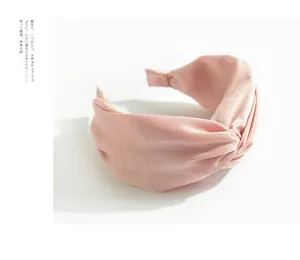 Detail eines rosa Satin-Stirnbands mit stilvollem Mittelknoten auf weißem Hintergrund