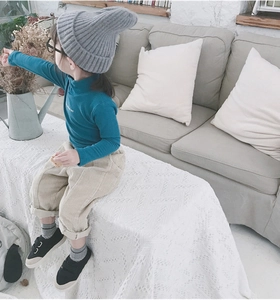 Close-up of child wearing a blue knitted turtleneck sweater and grey beanie hat