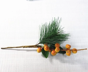 Detail of green artificial pine needle branch with orange berries for Christmas decor
