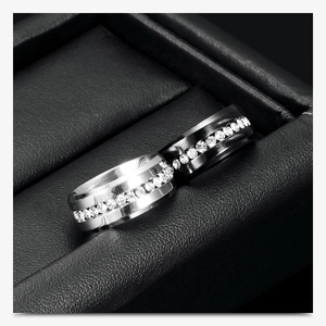 Macro view of brushed 8mm stainless steel band rings featuring a full row of set diamonds