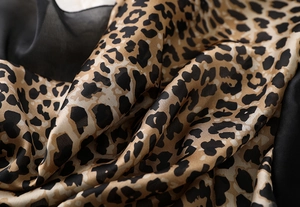 Macro shot of silk scarf fabric featuring classic leopard print and soft satin texture