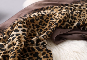 Macro shot of silk leopard print scarf with luxury satin gloss on white plush background