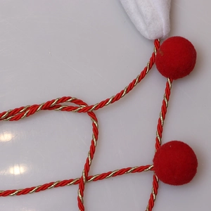 Festive Christmas hat decoration with red and gold braided ropes and soft plush balls