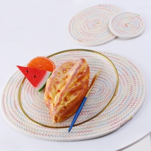 Three-piece beige woven cotton placemat set with a gold-rimmed plate and fresh fruit
