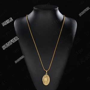 Detailed close-up of a gold oval Virgin Mary relief pendant on a woven metal chain