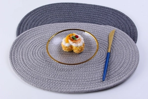 Close-up of oval hand-woven cotton placemats in grey and light grey with tableware