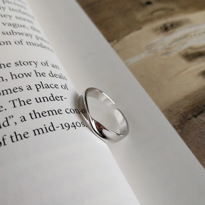 Minimalist 925 sterling silver Mobius ring with adjustable opening on an open book