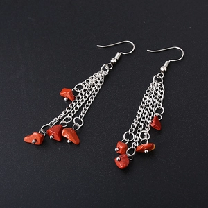 Macro shot of long silver tassel earrings with red natural crystal stone chips