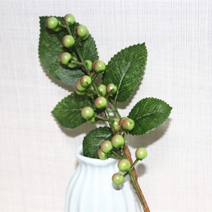 Artificial berry stem with green leaves in a white ceramic vase for home decoration