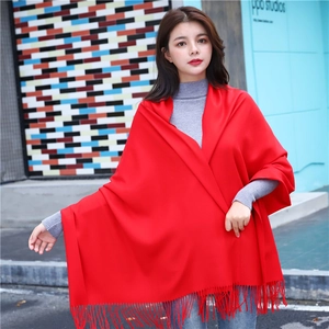 Detail of red cashmere-feel shawl with tassel fringes worn by a model in the city