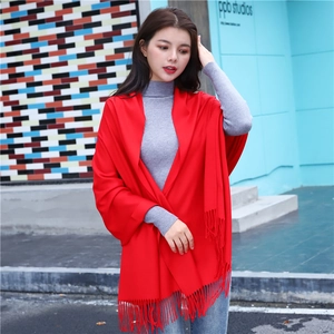Detailed view of long red scarf with fringe tassels worn as a warm winter shawl