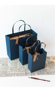 Three sizes of dark blue paper gift bags with black handles and vintage Thank You tags