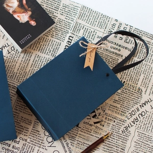 Minimalist navy blue gift paper bag with woven rope handles on vintage newspaper backdrop