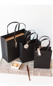 Detailed view of black paper gift bags in three sizes with Love tags on newspaper background