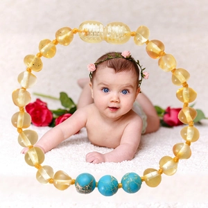 Baltic amber baby bracelet with turquoise beads on a soft white plush background