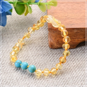 Detailed shot of Baltic amber baby bracelet with turquoise beads on woven texture background
