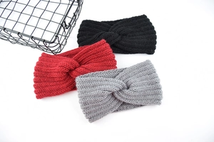 Close-up of three knitted cross-twist headbands in black, red, and grey wool texture