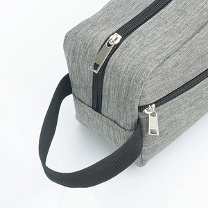 Detail of grey woven fabric toiletry bag with black zipper and silver metal puller