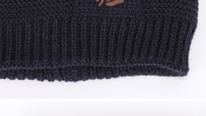 Detailed close-up of navy blue thick knit fabric with ribbing and brown leather patch