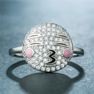 Vue macro d'une bague argentée avec un visage mignon, cristaux pavés et détails émail