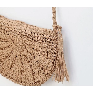 Detailed macro view of radial woven straw pattern and tassel on a handmade beach bag