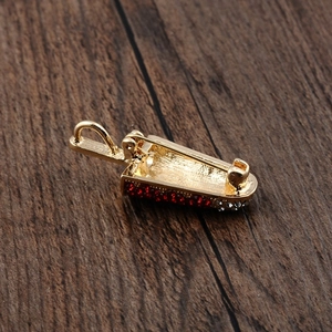 Macro shot of gold ice cream brooch with red rhinestones on a dark wood texture