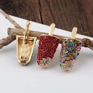 Detail of popsicle brooches with colorful rhinestones and golden base on white background