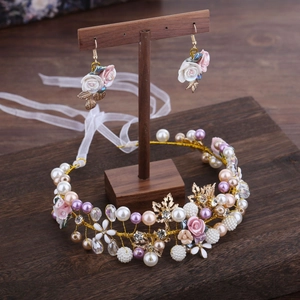 Handmade bridal headband and earring set with ceramic flowers and pearls on wooden stand