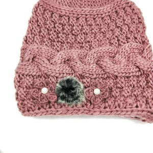 Detailed knit texture of pink winter hat with faux fur pom pom and pearl embellishments