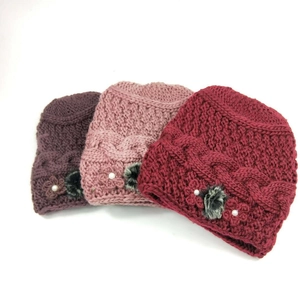 Detail of cable knit winter hats for women with floral accents and faux pearl centers
