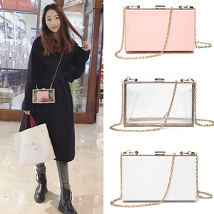 Detailed view of acrylic clutch bag with gold chain strap in pink and white