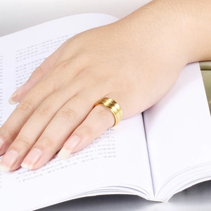 Minimalist 8mm gold stainless steel ring with double matte texture on an open book