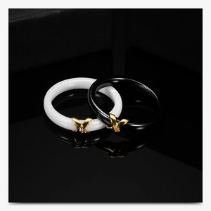 Macro detail of black and white ceramic rings featuring gold cross-over pavé diamond accents