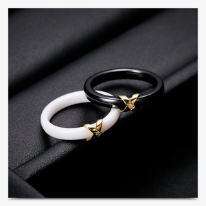 Macro shot of black and white ceramic rings with gold X-cross and small zircon stones