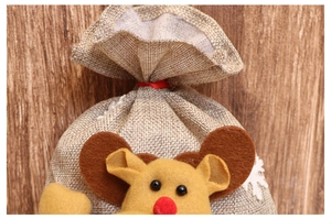 Detail of Christmas burlap gift bag featuring a plush reindeer and festive snowflake patterns
