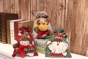Detailed view of three Christmas burlap drawstring gift bags with plush holiday figures