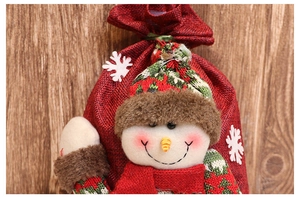 Detail of red burlap Christmas bag with 3D plush snowman on a warm wood background