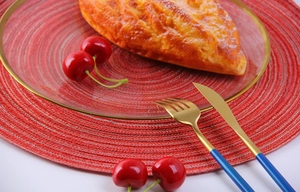 Macro shot of red round ramie placemat with glass plate and stainless steel cutlery set